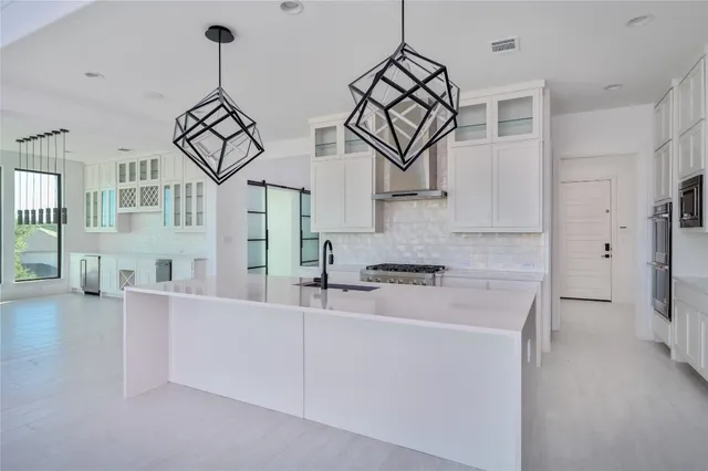 a view of a kitchen with stainless steel appliances a stove a refrigerator and chandelier