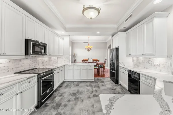 a large kitchen with a stove top oven a sink dishwasher a refrigerator and white cabinets with wooden floor