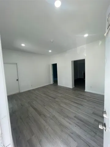a view of an empty room with wooden floor and closet