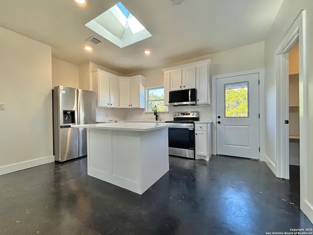 a kitchen with stainless steel appliances a microwave a stove a sink dishwasher a refrigerator and a stove with wooden floor