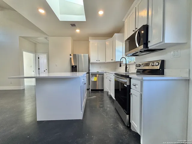 a kitchen with stainless steel appliances granite countertop a stove a sink and a refrigerator