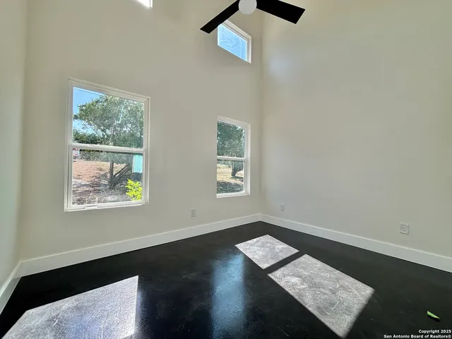 an empty room with wooden floor a ceiling fan and a window
