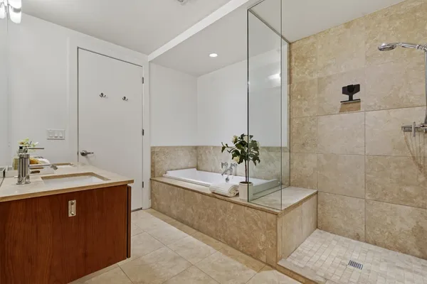 a spacious bathroom with a tub sink and mirror