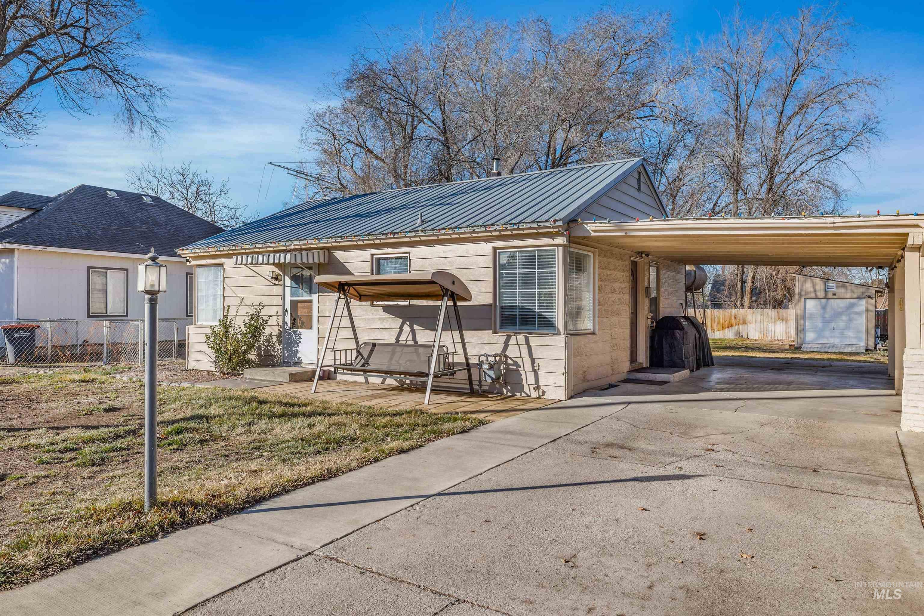 View of front facade featuring an attached carport, concrete driveway, and a metal roof