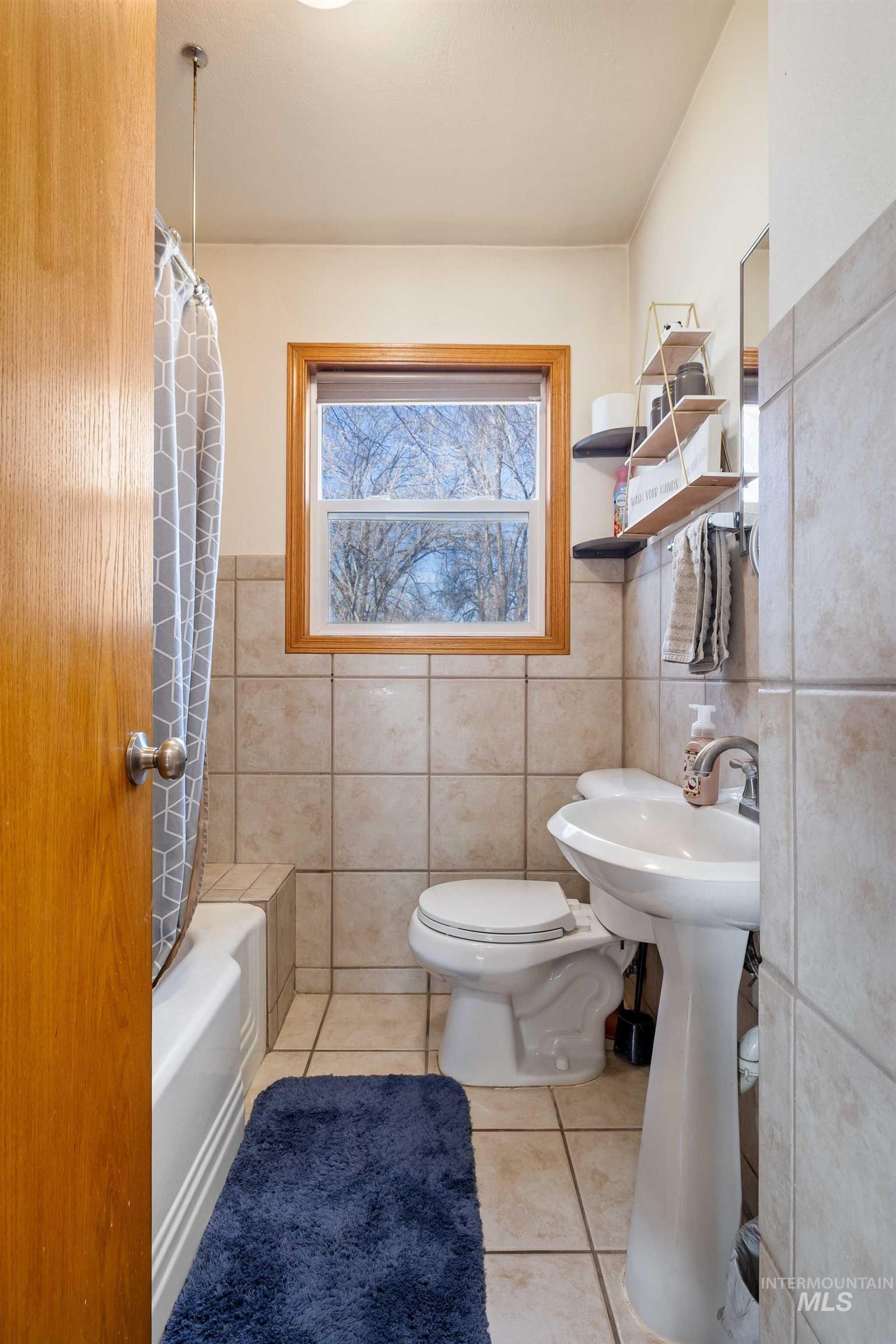 753 Ash Street Twin Falls, ID 83301 - Photo 16 of 25 Bathroom with shower / bath combo, light tile patterned floors, tile walls, and wainscoting