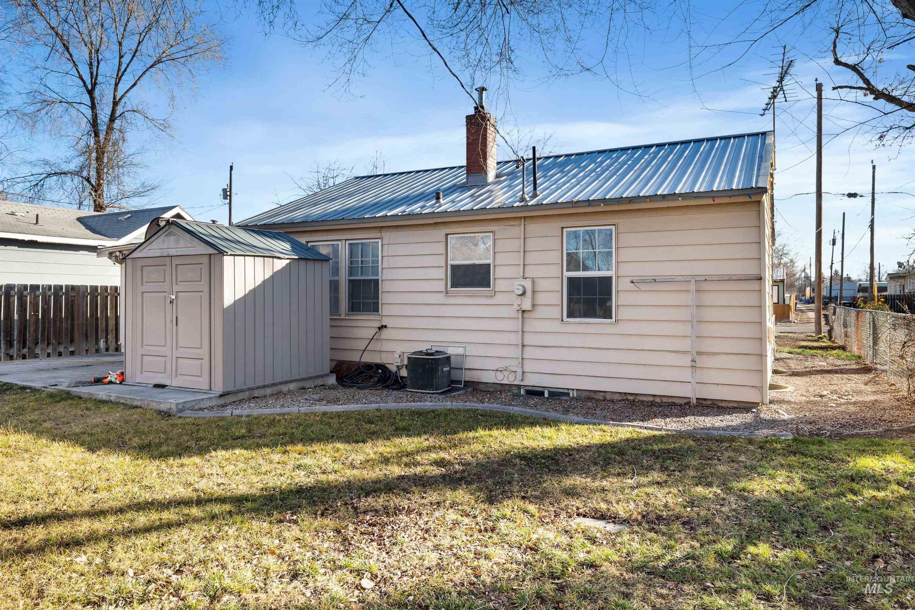 753 Ash Street Twin Falls, ID 83301 - Photo 25 of 25 Rear view of house with a fenced backyard, a metal roof, a chimney, and a storage unit