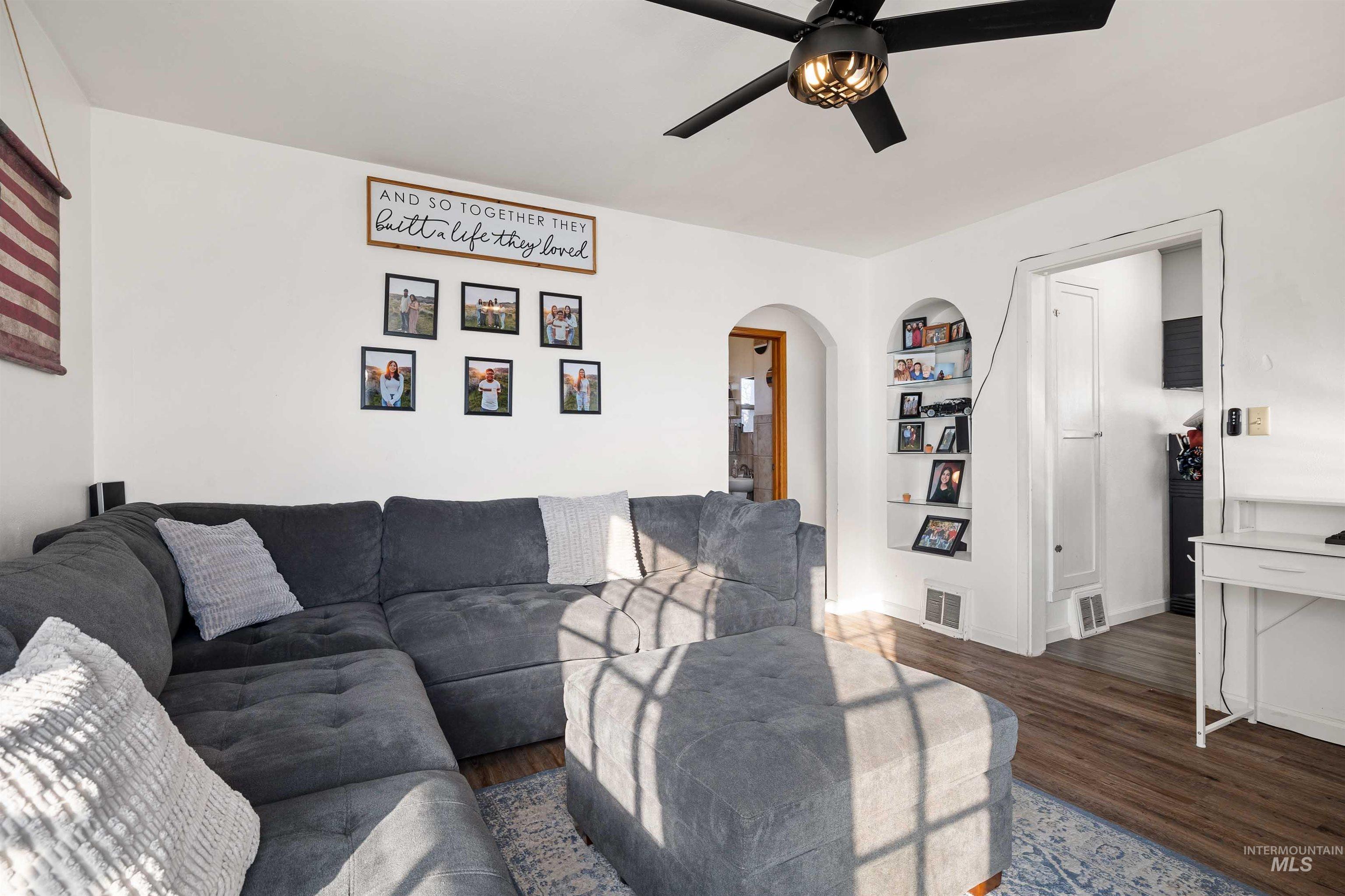 753 Ash Street Twin Falls, ID 83301 - Photo 5 of 25 Living room with arched walkways, built in shelves, dark wood-style floors, and ceiling fan