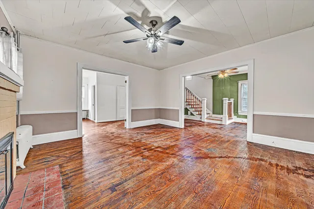 an empty room with wooden floor chandelier and windows