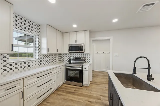 a kitchen with granite countertop a stove a sink and a microwave