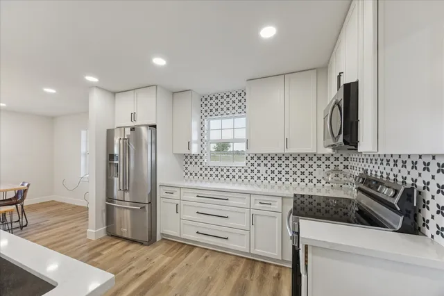 a kitchen with granite countertop a refrigerator and a stove top oven