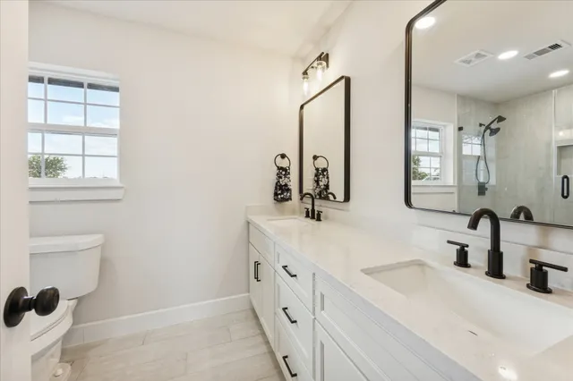 a bathroom with a double vanity sink window and mirror
