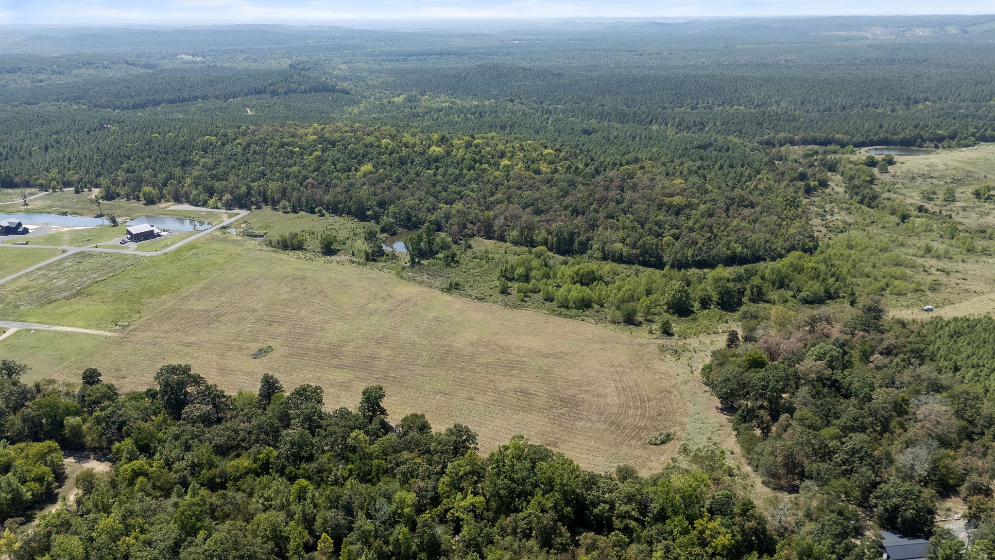 0 Rutty Pne Ridge Broken Bow, OK 74728 - Photo 4 of 22 Expansive land offering diverse topography, including cleared fields, dense mature tree coverage, and visible water features