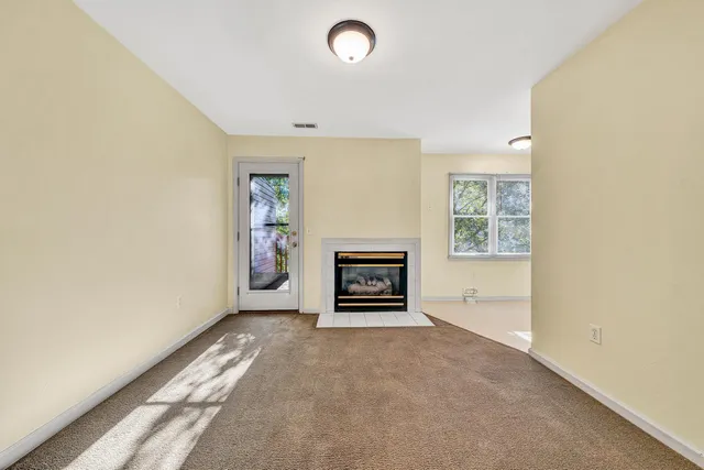 an empty room with windows and fireplace