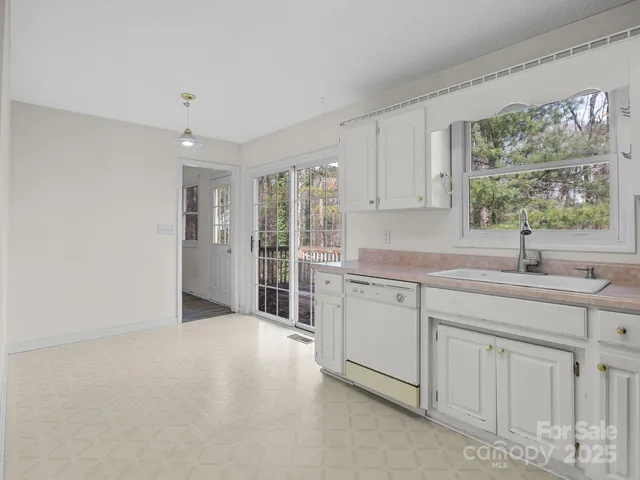 a kitchen with white cabinets and window