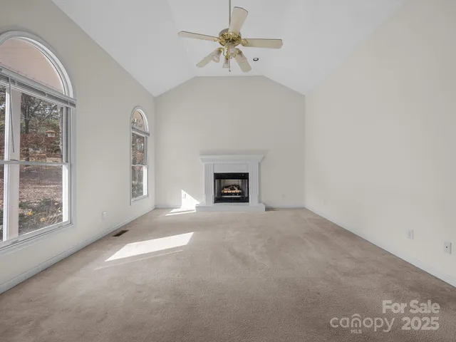 an empty room with windows and fireplace