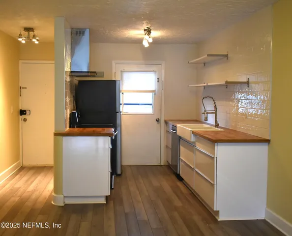 a kitchen with sink a refrigerator and wooden floor