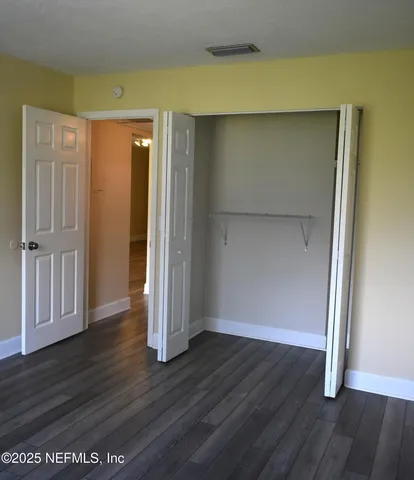 an empty room with wooden floor and closet