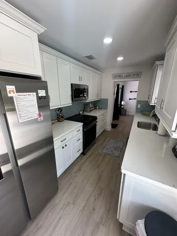 a large white kitchen with wooden floor