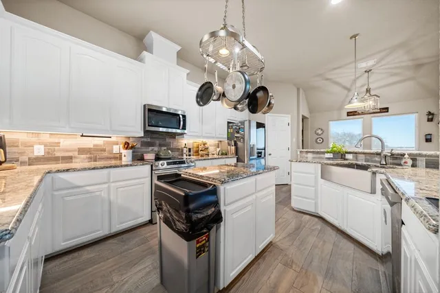 a kitchen with cabinets a sink dishwasher and a stove with wooden floor