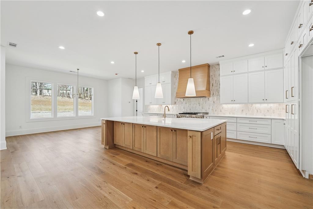 3315 Bold Springs Road Dacula, GA 30019 - Photo 11 of 63 a large kitchen with stainless steel appliances granite countertop a sink a stove a refrigerator and white cabinets with wooden floor