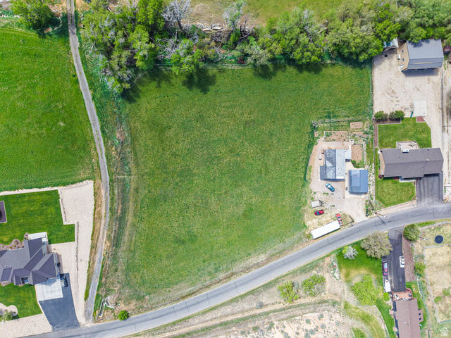 94 Spring Canyon Road Coalville, UT 84017 - Photo 20 of 50 Expansive green property featuring a paved road frontage, mature trees bordering the perimeter, a large open field, and two structures