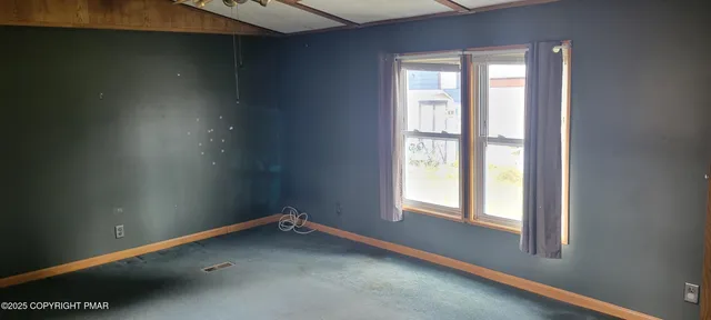 a view of an empty room with a window and a kitchen