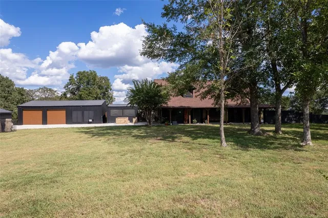 a backyard of a house with wooden fence and a large tree