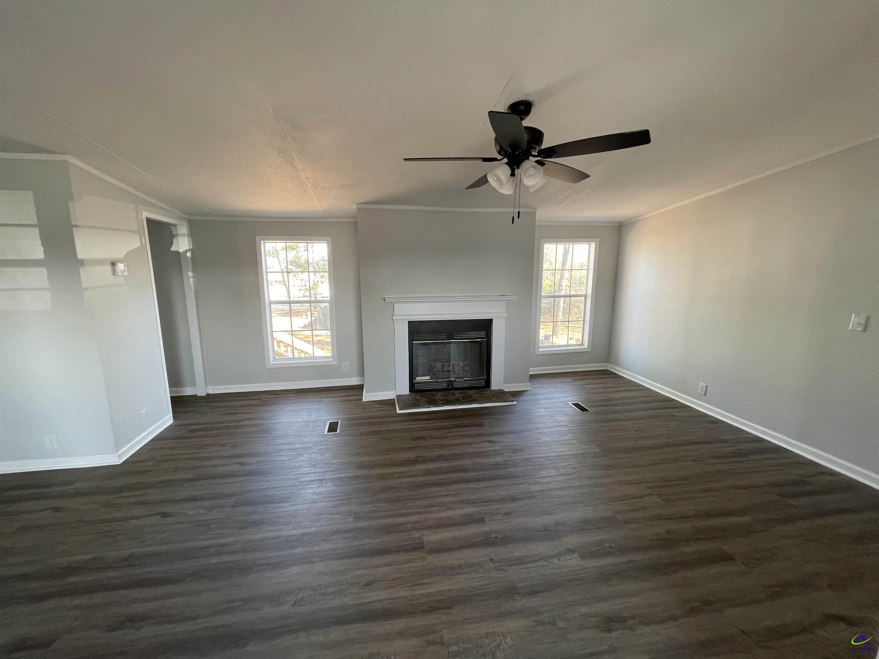 306 Dennard Road Unadilla, GA 31091 - Photo 2 of 14 an empty room with wooden floor fireplace and windows