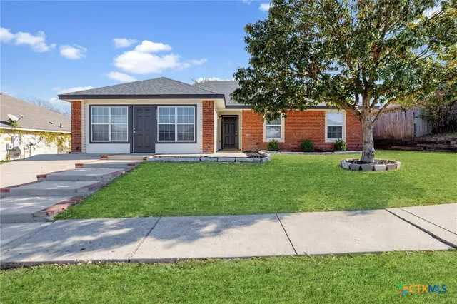 a front view of a house with a yard and trees