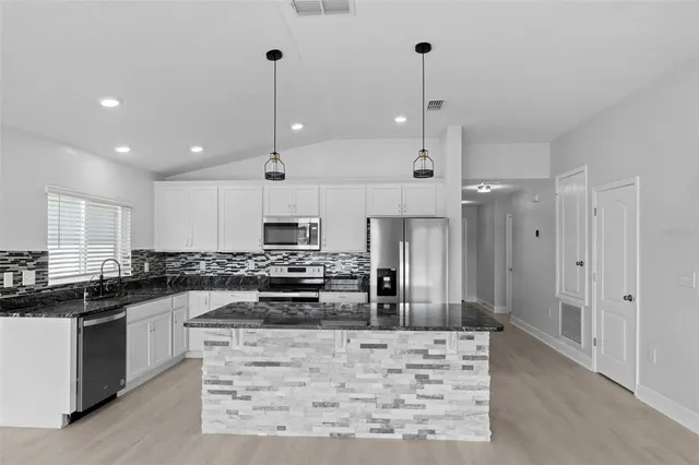 a kitchen with stainless steel appliances granite countertop a refrigerator a sink and a stove