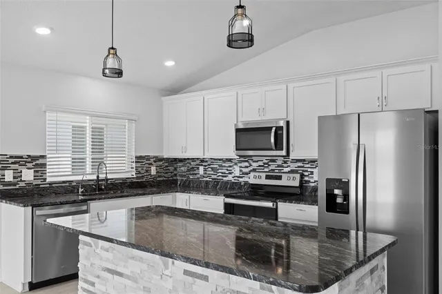 a kitchen with stainless steel appliances granite countertop a sink and a refrigerator