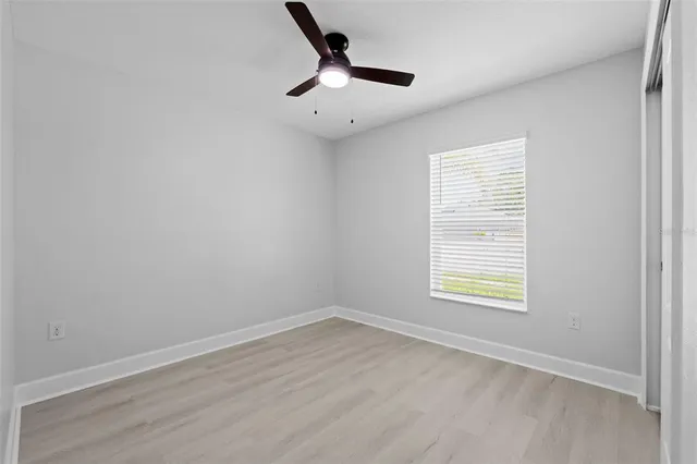a view of an empty room with a window and wooden floor