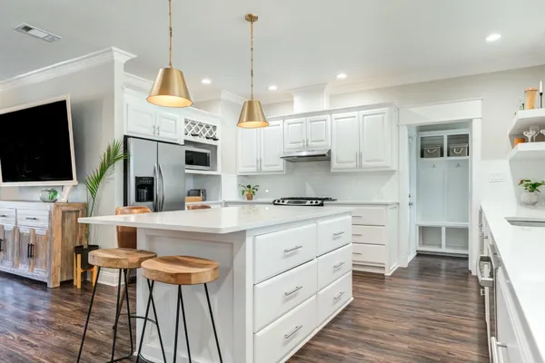 a kitchen with stainless steel appliances kitchen island granite countertop a stove a sink and a refrigerator with wooden floor