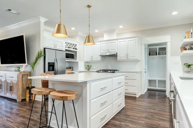 a kitchen with stainless steel appliances kitchen island granite countertop a stove a sink and a refrigerator with wooden floor