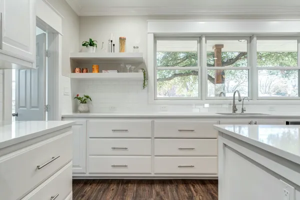 a kitchen with white cabinets and a window