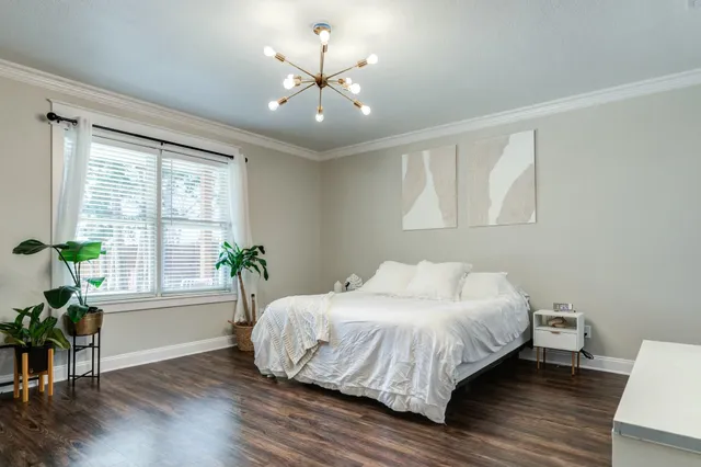 a bedroom with a bed windows and wooden floor
