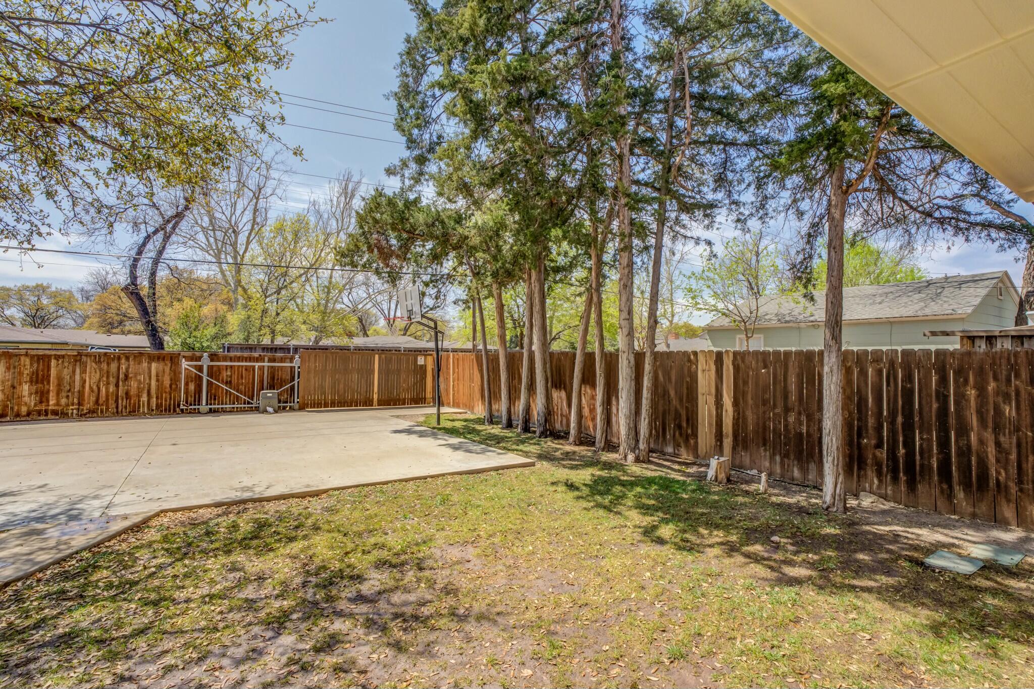 3219 22nd Street Lubbock, TX 79410 - Photo 48 of 51 a backyard of a house with large trees and wooden fence