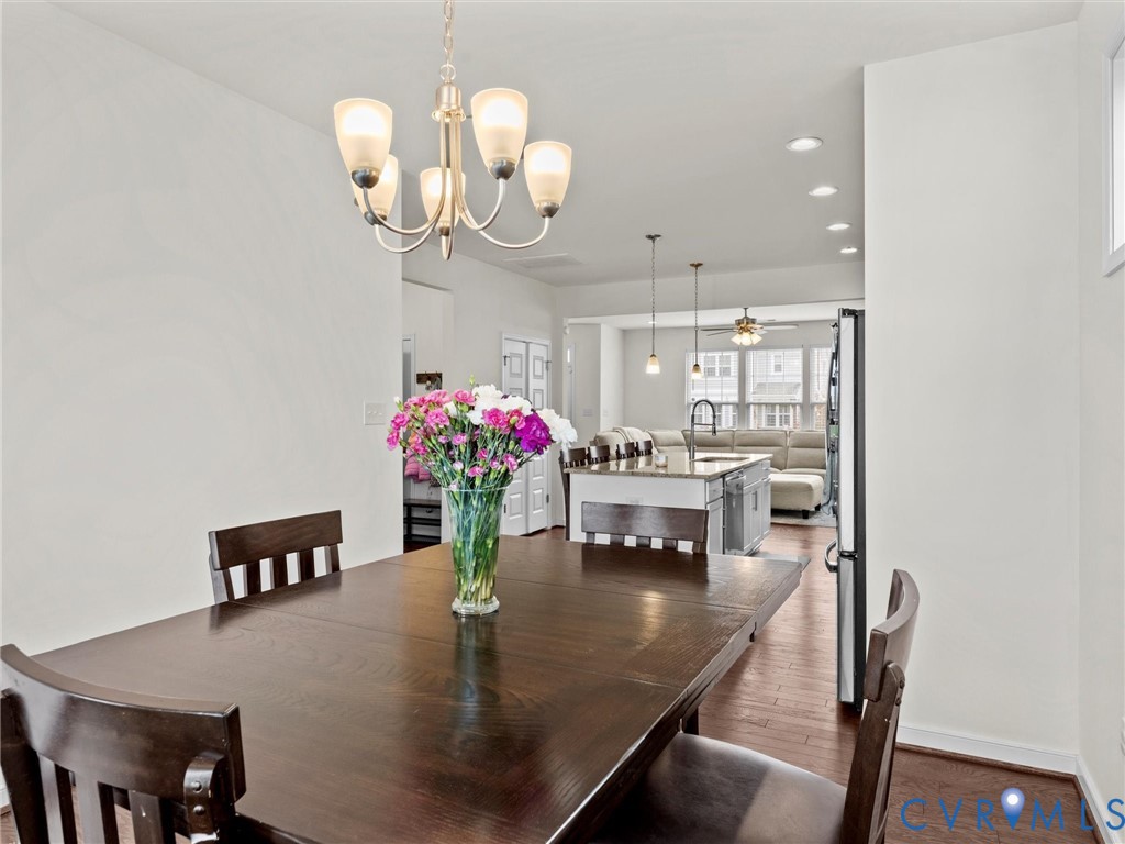 6135 Buntline Lane Richmond, VA 23234 - Photo 16 of 34 a dining room with wooden floor a chandelier a wooden table and chairs