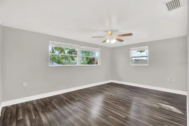 a view of an empty room with wooden floor and a window