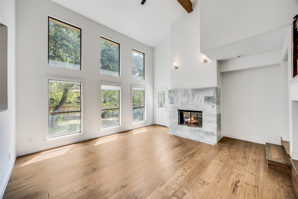 a view of an empty room with wooden floor fireplace and a window