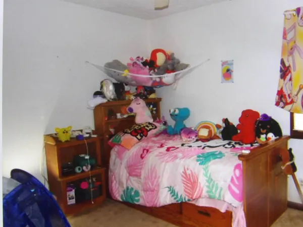 a bedroom with a bed and teddy bear on bed