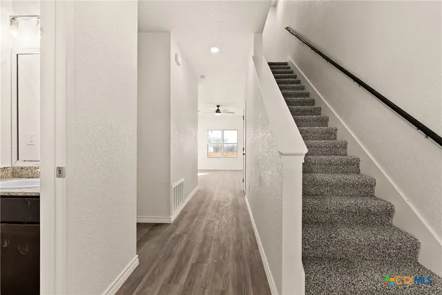 a view of a hallway with wooden floor and staircase