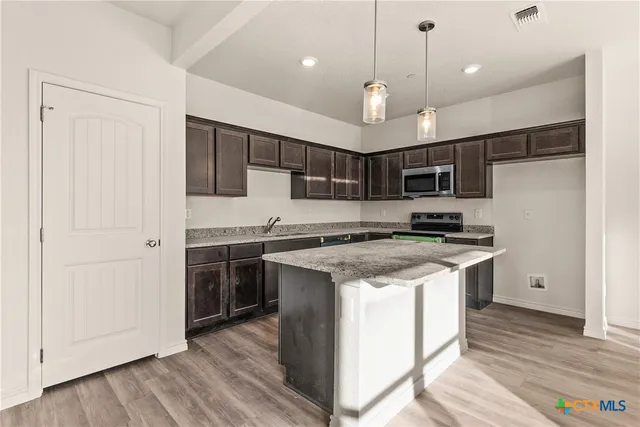 a kitchen with kitchen island a sink stainless steel appliances and cabinets