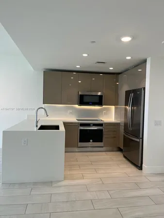 a large kitchen with stainless steel appliances a large counter top and a refrigerator