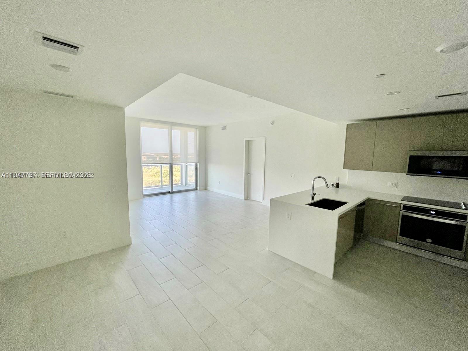 2000 Metropica Way, Unit 1602 Sunrise, FL 33323 - Photo 8 of 50 a large white kitchen with a stove a sink and a microwave