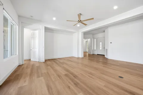 a view of empty room with wooden floor and fan