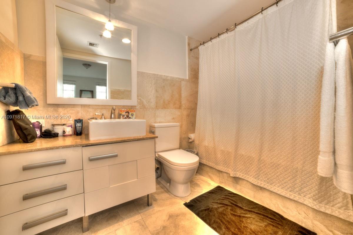 3540 Main Highway, Unit 301 Miami, FL 33133 - Photo 17 of 29 a bathroom with a sink a toilet and a mirror