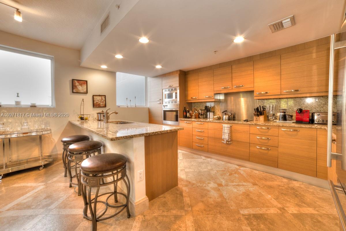 3540 Main Highway, Unit 301 Miami, FL 33133 - Photo 5 of 29 a kitchen with stainless steel appliances kitchen island granite countertop a sink and cabinets