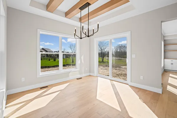 a view of an empty room with wooden floor and windows
