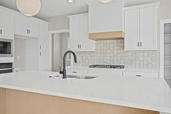 a kitchen with kitchen island a sink a stove and white cabinets